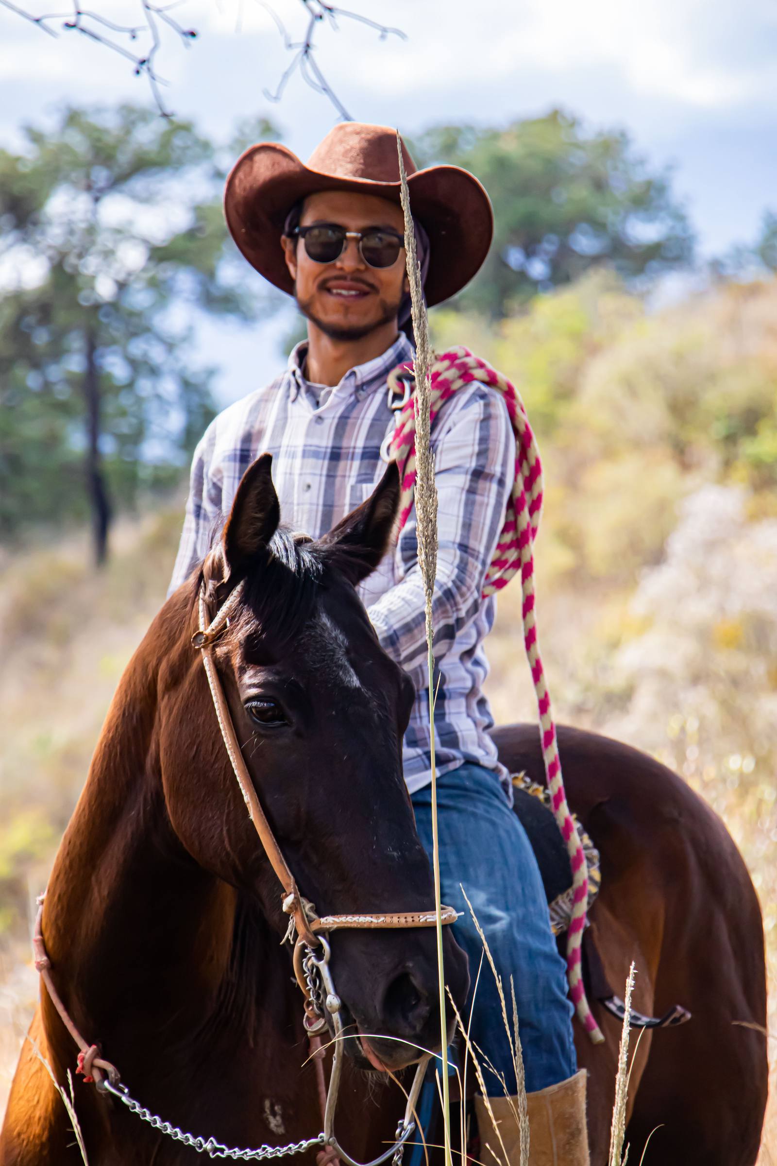 Uno de los muchachos del rancho a caballo, sombrero y reata en mano