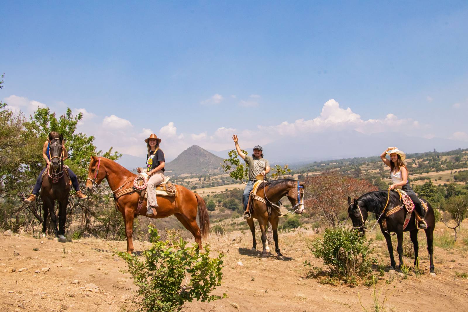 Grupo de jinetes en la Ruta del Volcán con el Popocatépetl y el Iztaccíhuatl al fondo