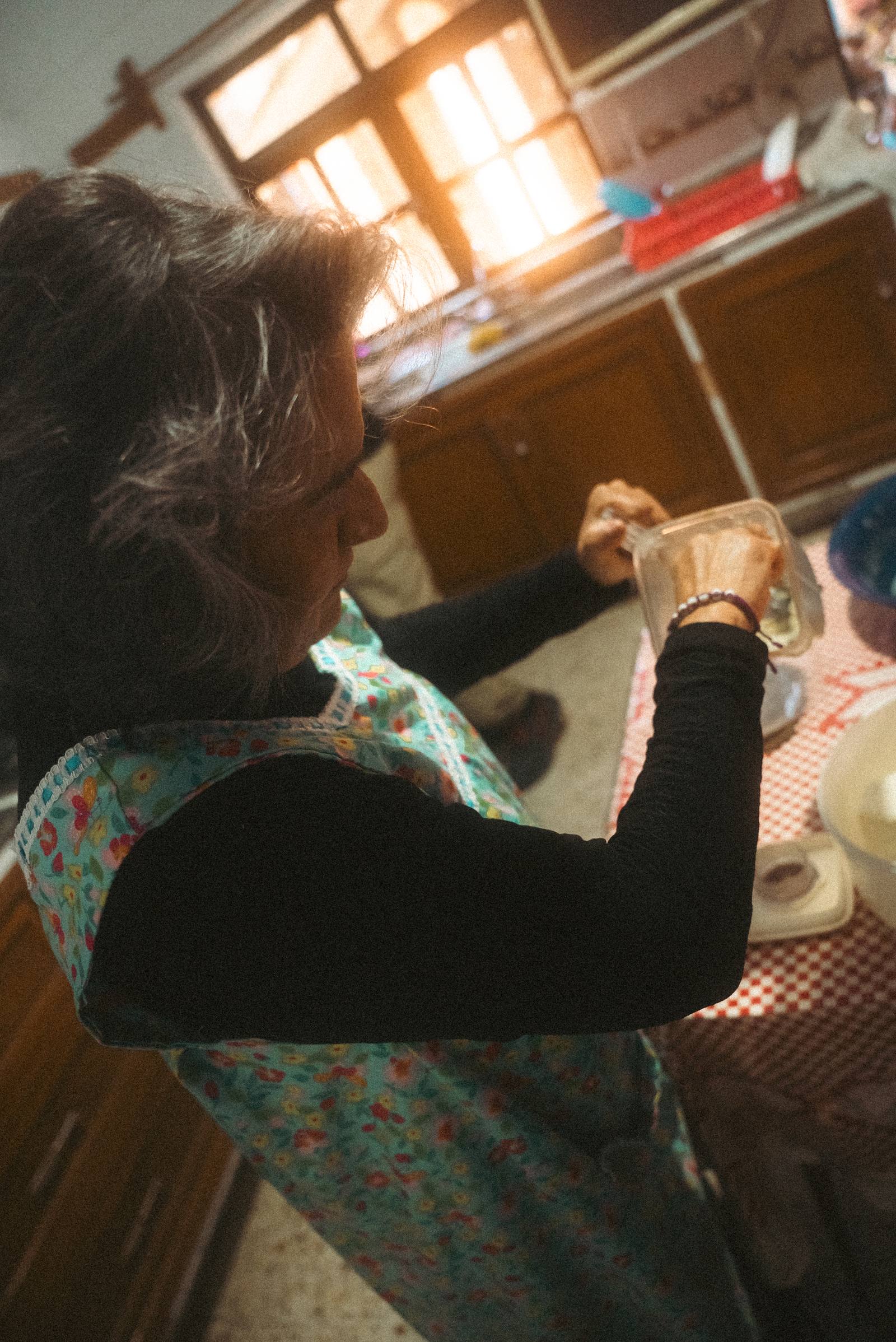 Doña Patricia con mandil floreado a contraluz en la cocina